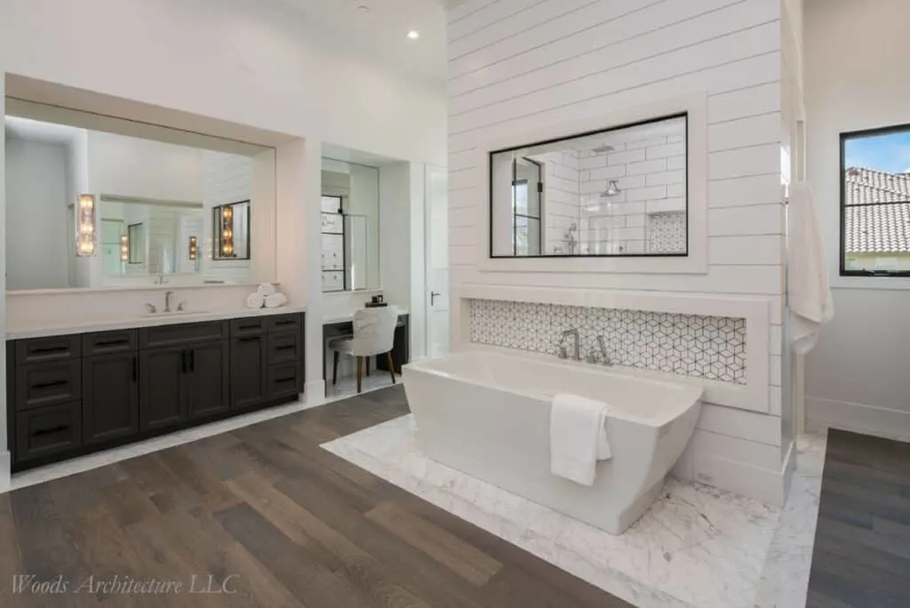 A large bathroom with a free standing tub and a wall behind it with white shiplap.