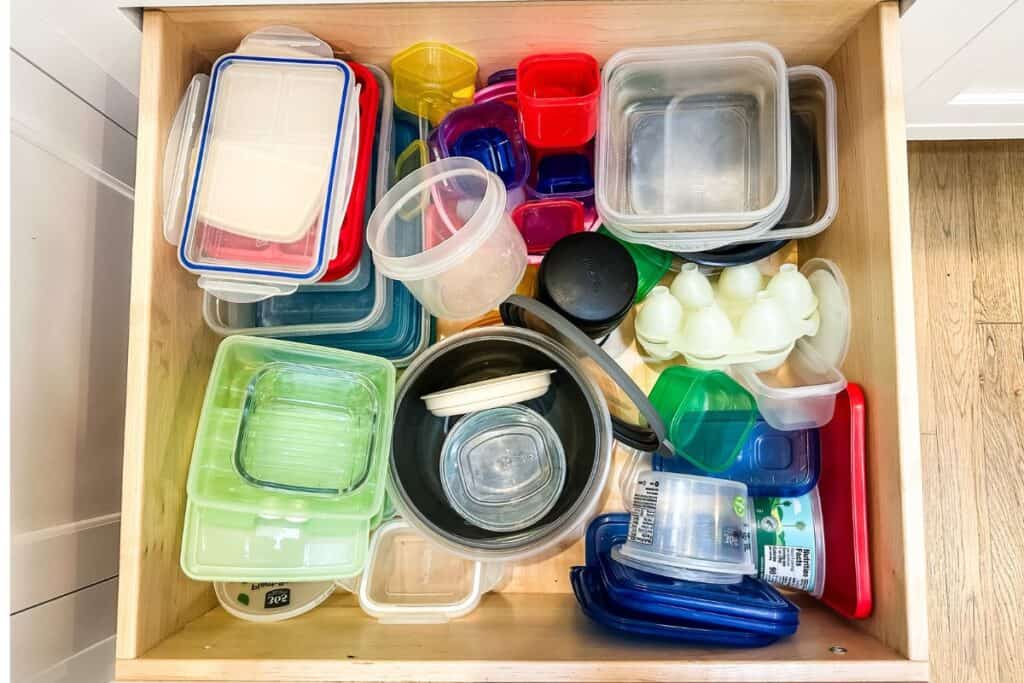 A messy drawer of plastic containers.