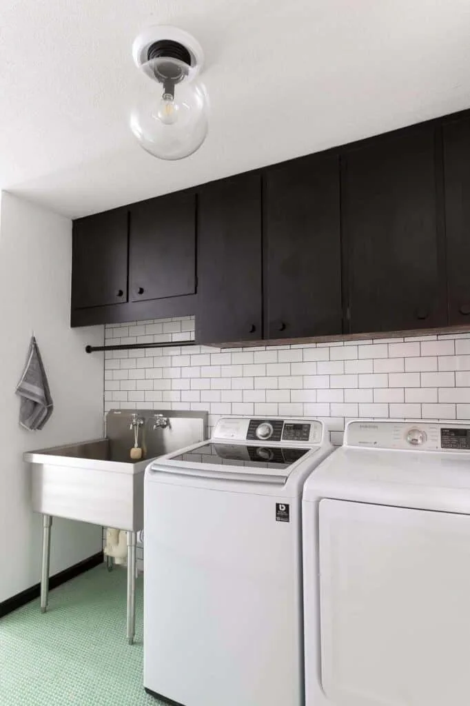 An industrial black and white laundry room with light green tile floors.