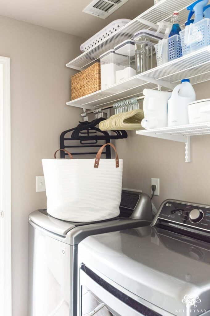 Laundry room with white wire shelves and lots of storage bins on them.