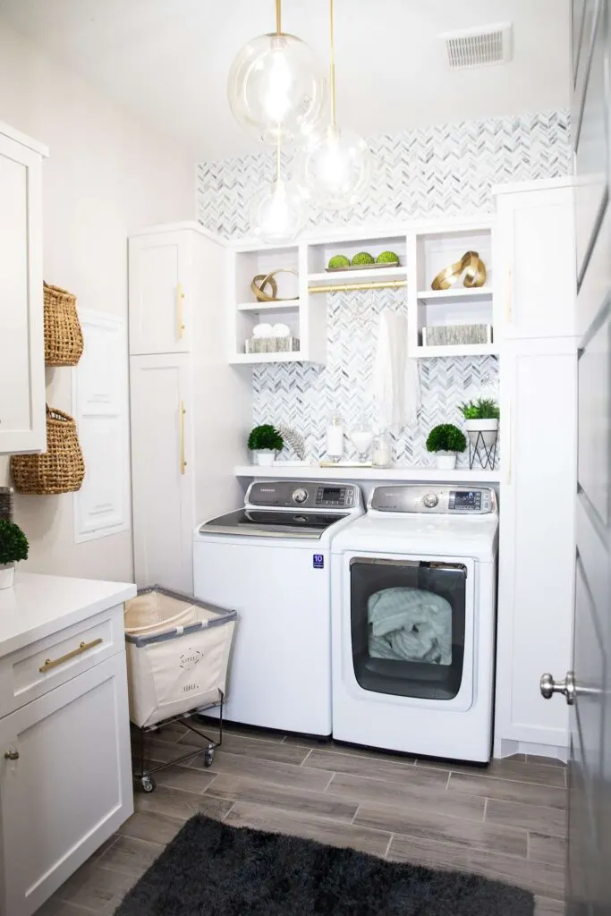 A white laundry room with marble tile backsplash in a chevron pattern.