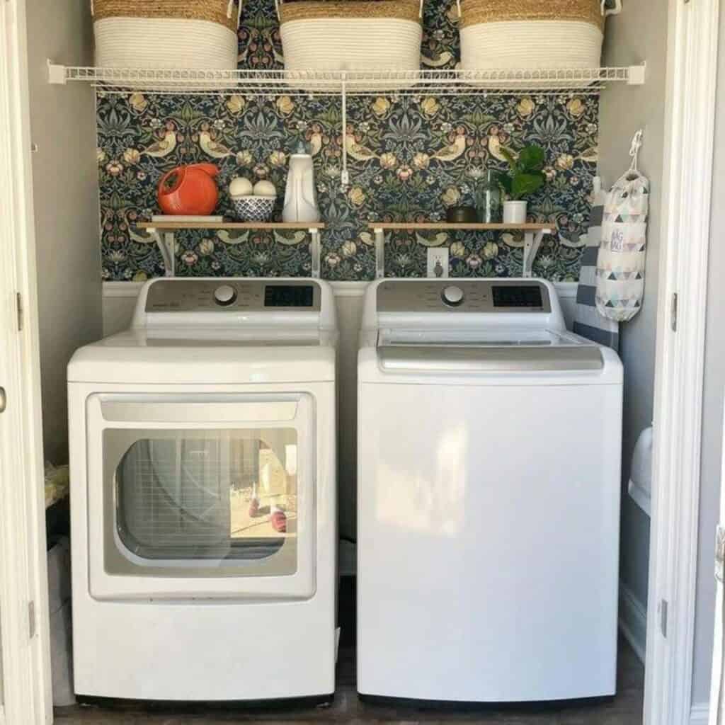 A laundry room with a decorative wallpaper on the back wall.