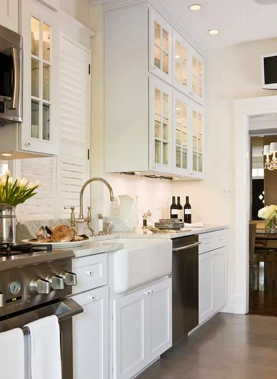 Soft Chamois on kitchen cabinets with a farmhouse sink and a window above with shutters.