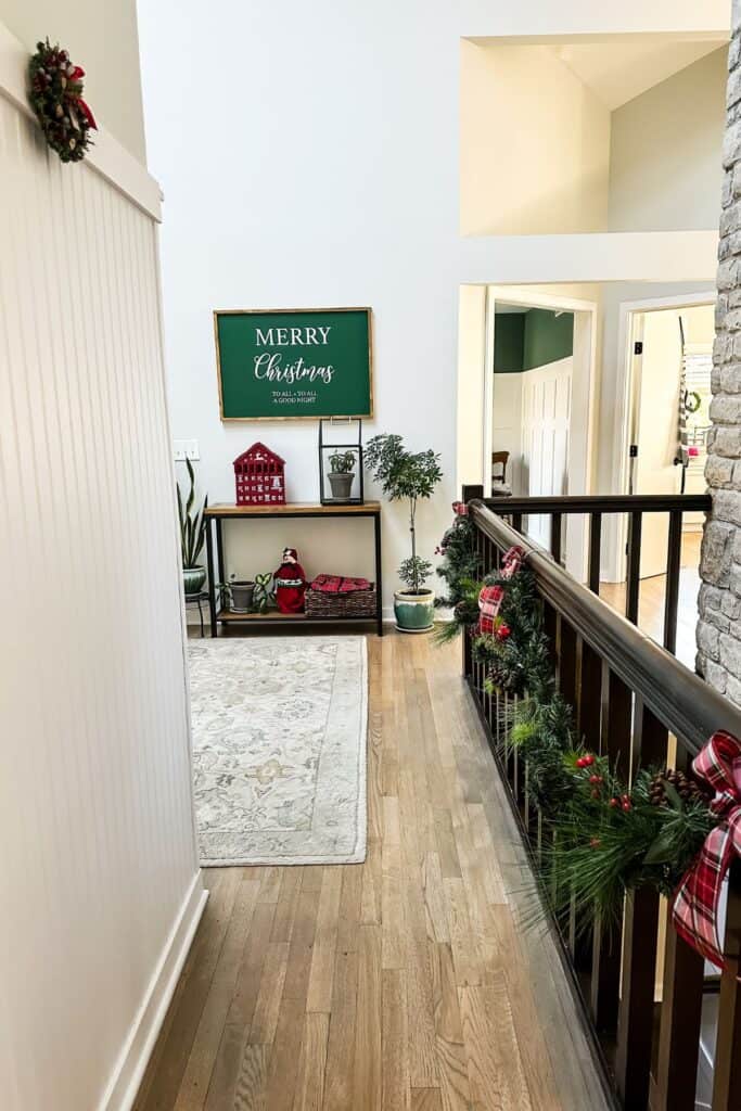 Entryway table with a merry christmas sign above, lots of plants and an advent calendar.