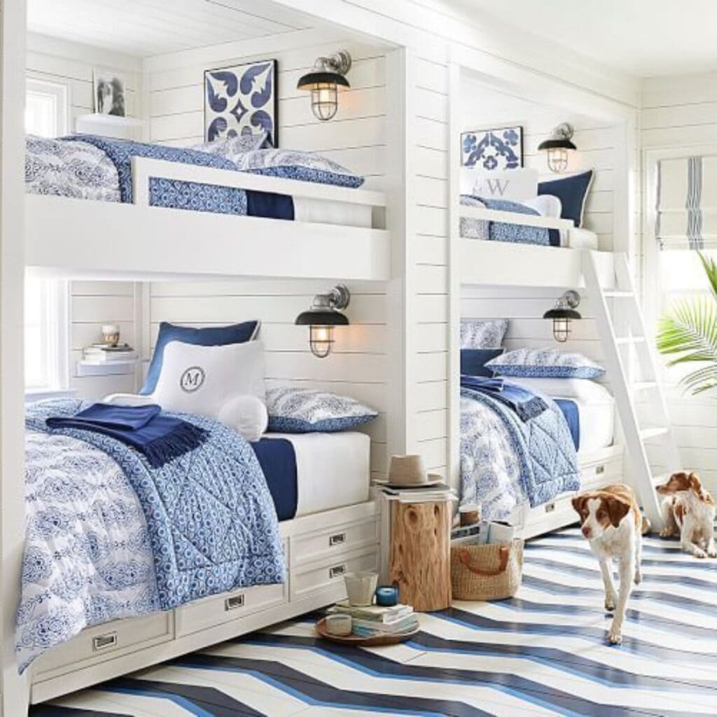 A bunk room with white shiplap walls and blue and white bedding.