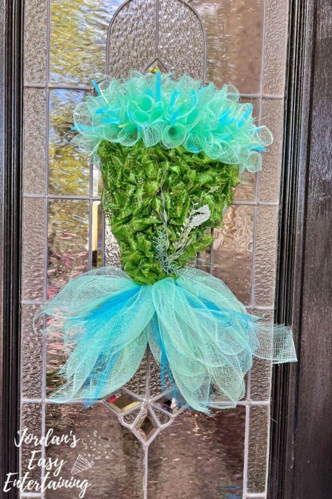 A ribbon wreath made to look like a mermaid with blue ribbon and green.