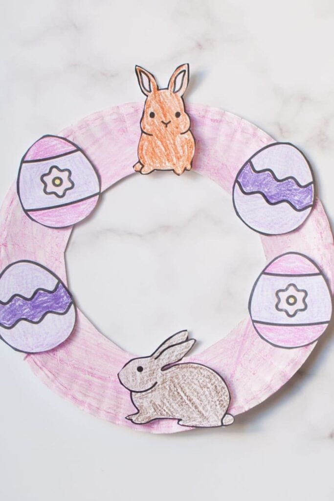 A paper plate crafted to look like a wreath with eggs and bunnys.