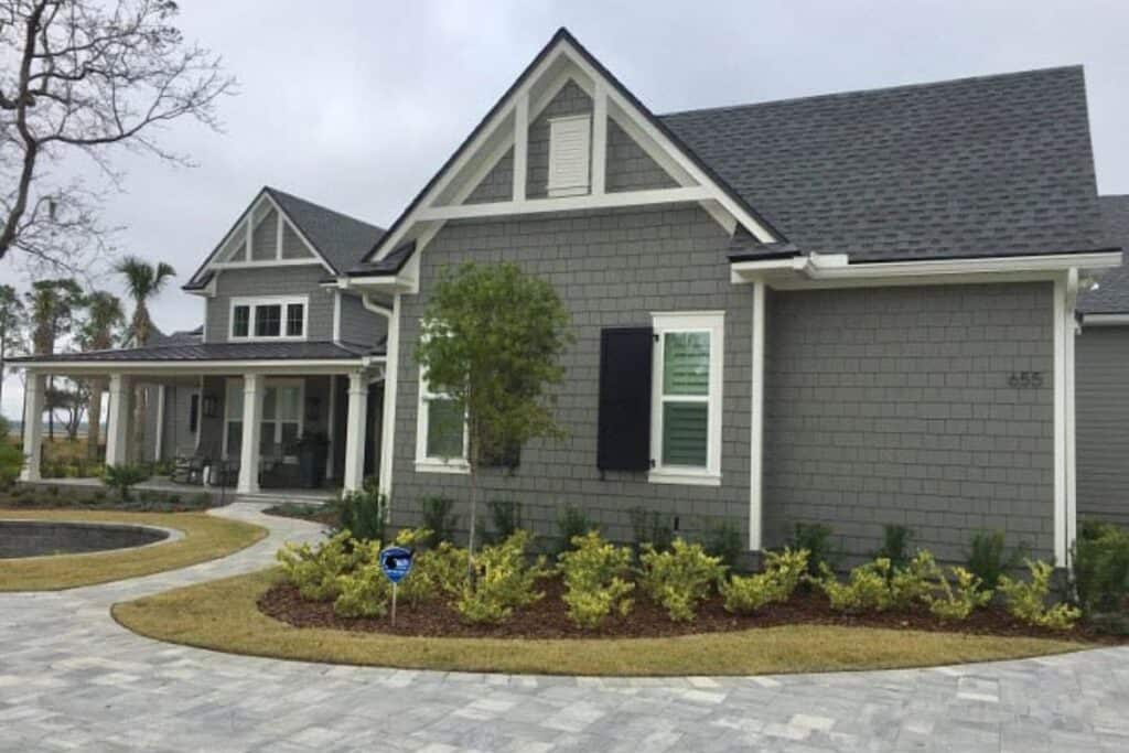 Chelsea Gray on the exterior of the home with white trim, lots of landscaping and a paver driveway.