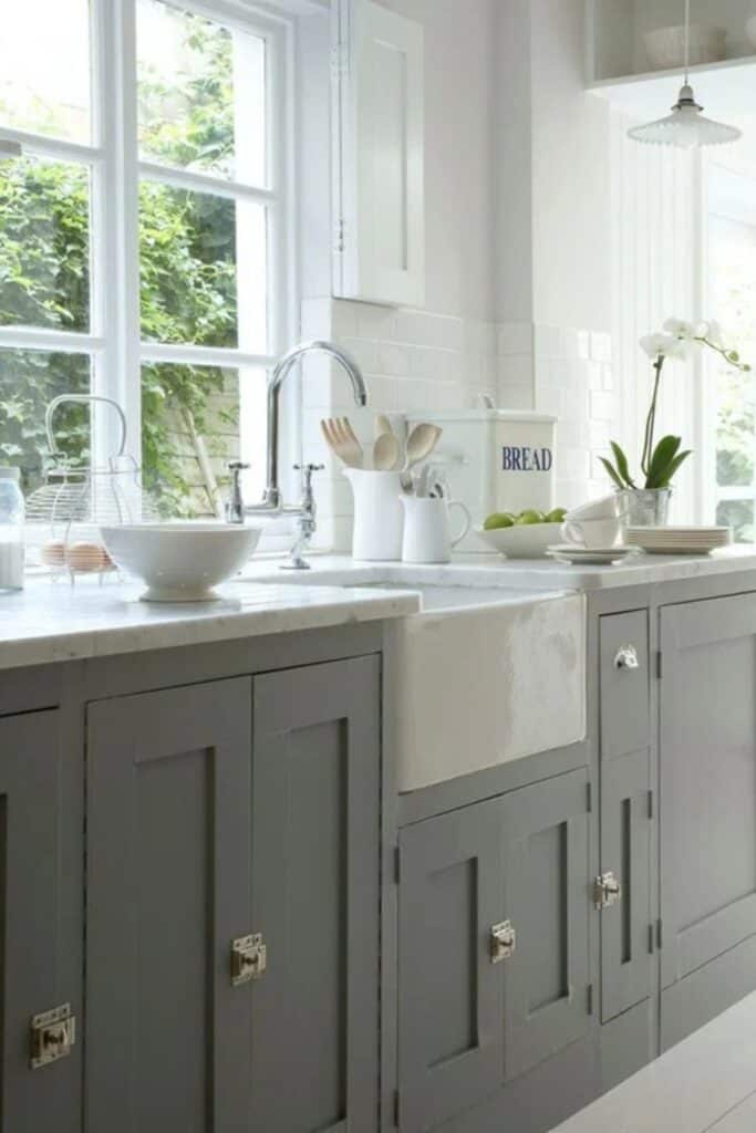 Chelsea Gray on cabinets with silver hardware, marble counters and a lot of windows.