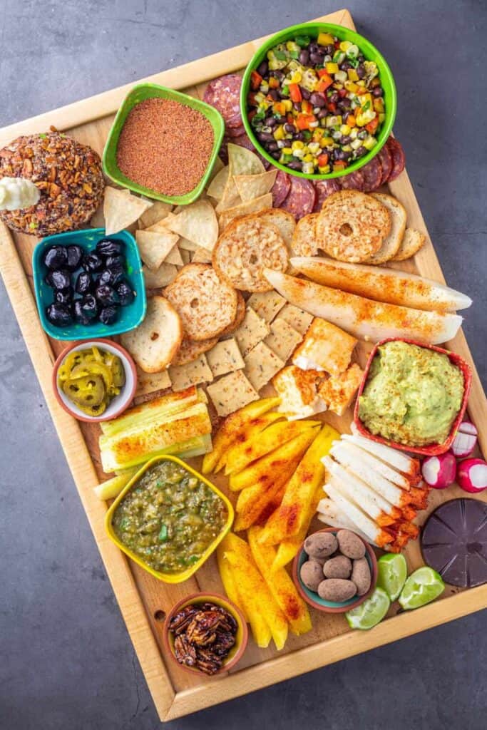 A mexican charcuterie board on a light wood cutting board with a dark gray background.