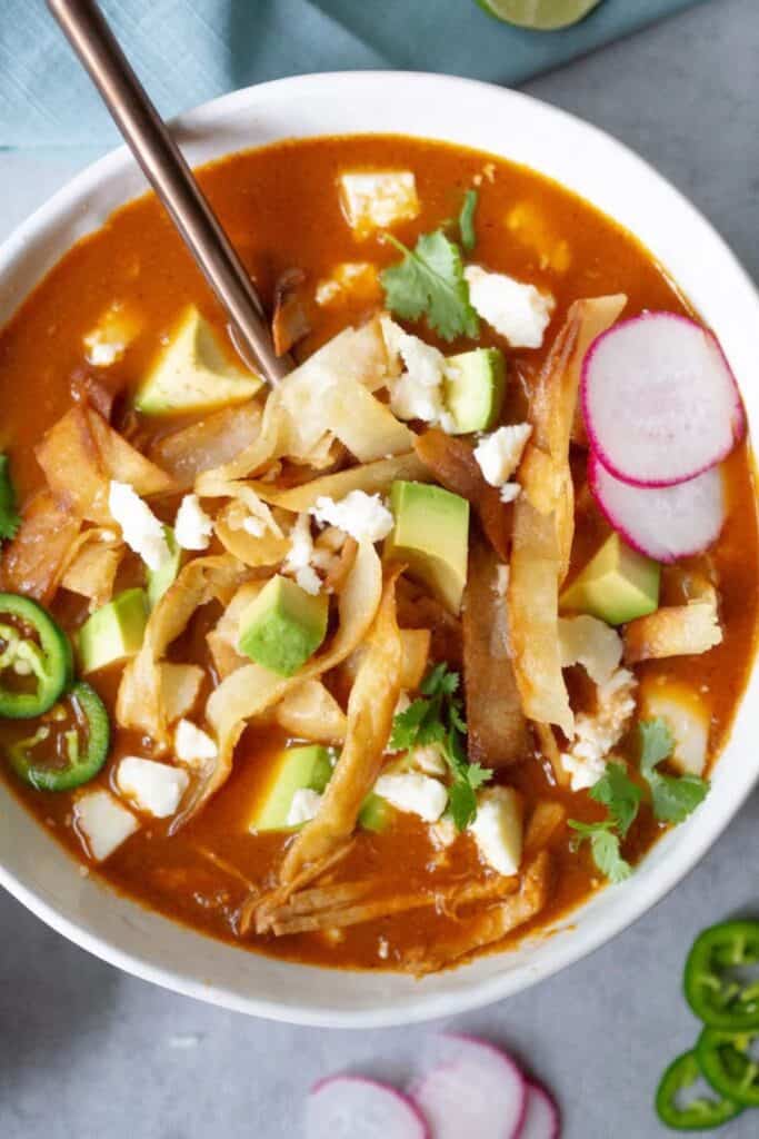 Chicken tortilla soup in a white bowl with a spoon.