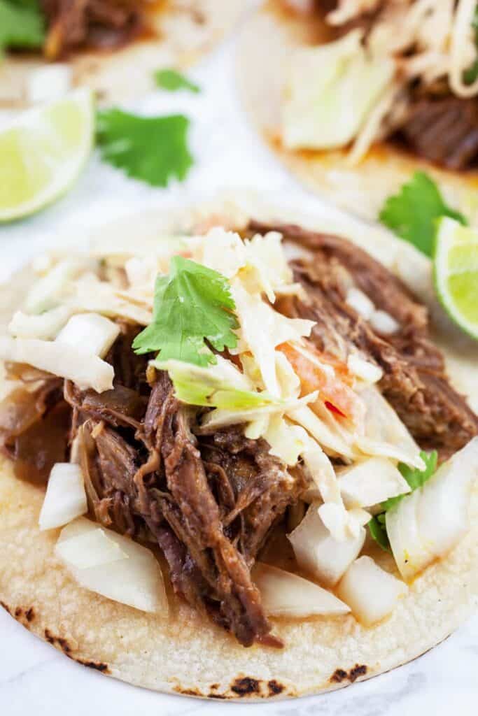 Barbacoa tacos with a chipotle slaw on a white plate.