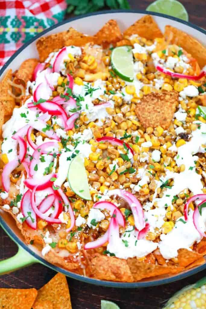 Mexican street corn tacos with cilantro, limes, and red onions on top.
