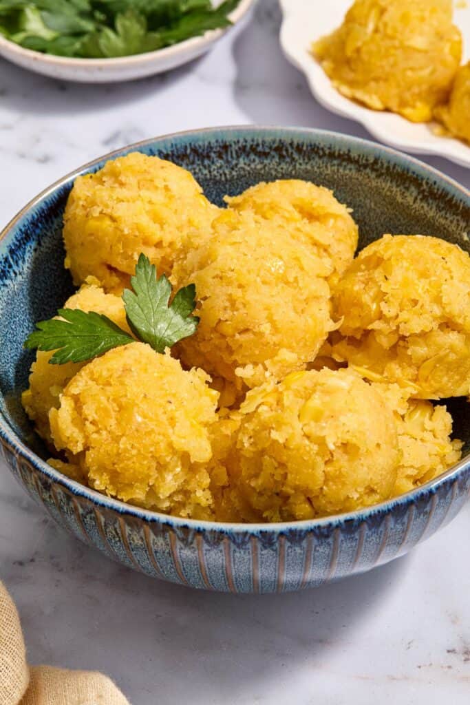 Mexican street corn cake in balls in a blue bowl topped with cilantro.