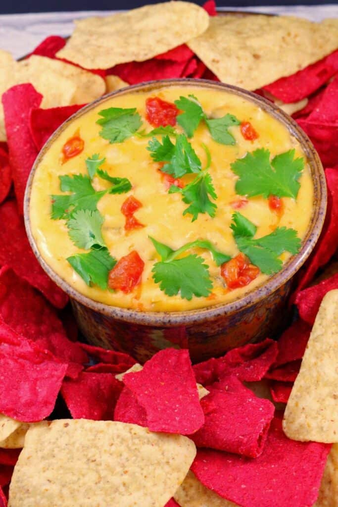 Chili con queso with red and white chips topped with cilatro.