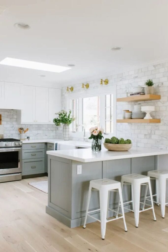 Gray cabinets on the bottom and white cabinets on the top, which counters, and a marble subway tile backsplash.