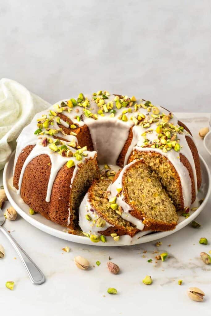 Pistachio bundt cake with white icing and chopped pistachios on top.