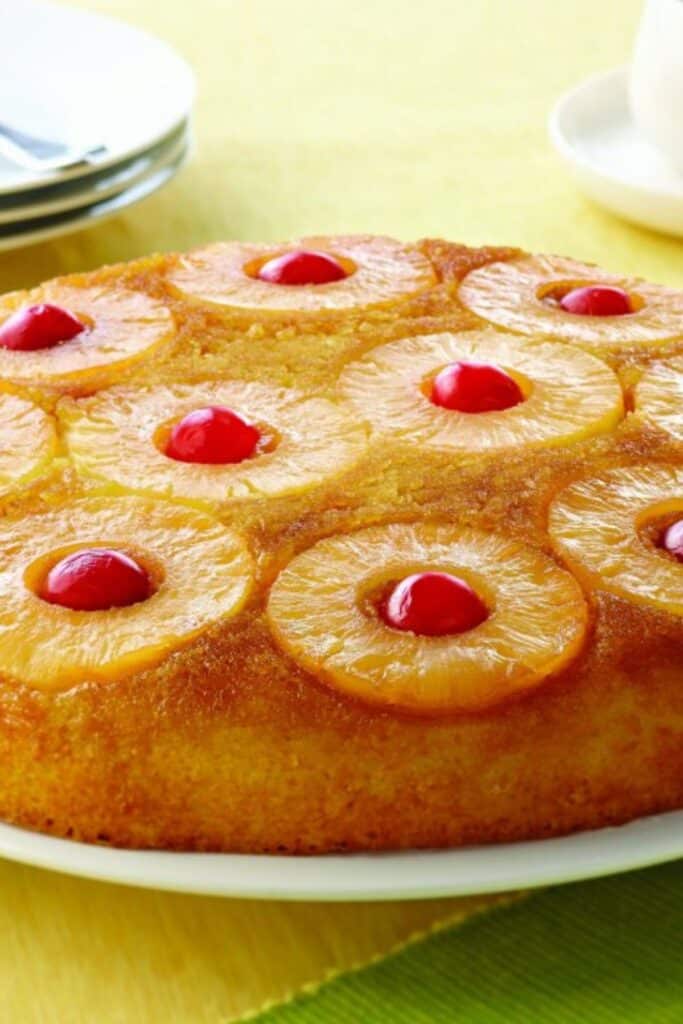 Pineapple Upside down cake with cherries in the center of the pineapple slices on a green plate.