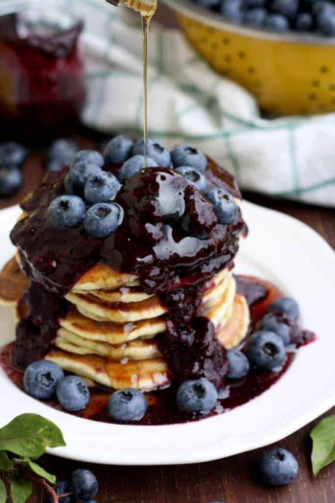 stacked pancakes with a blueberry sauce on a white plate