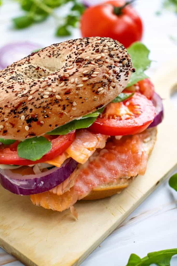smoked salmon on an everything bagel with red onion, cheese, tomatoe slices and lettuce.