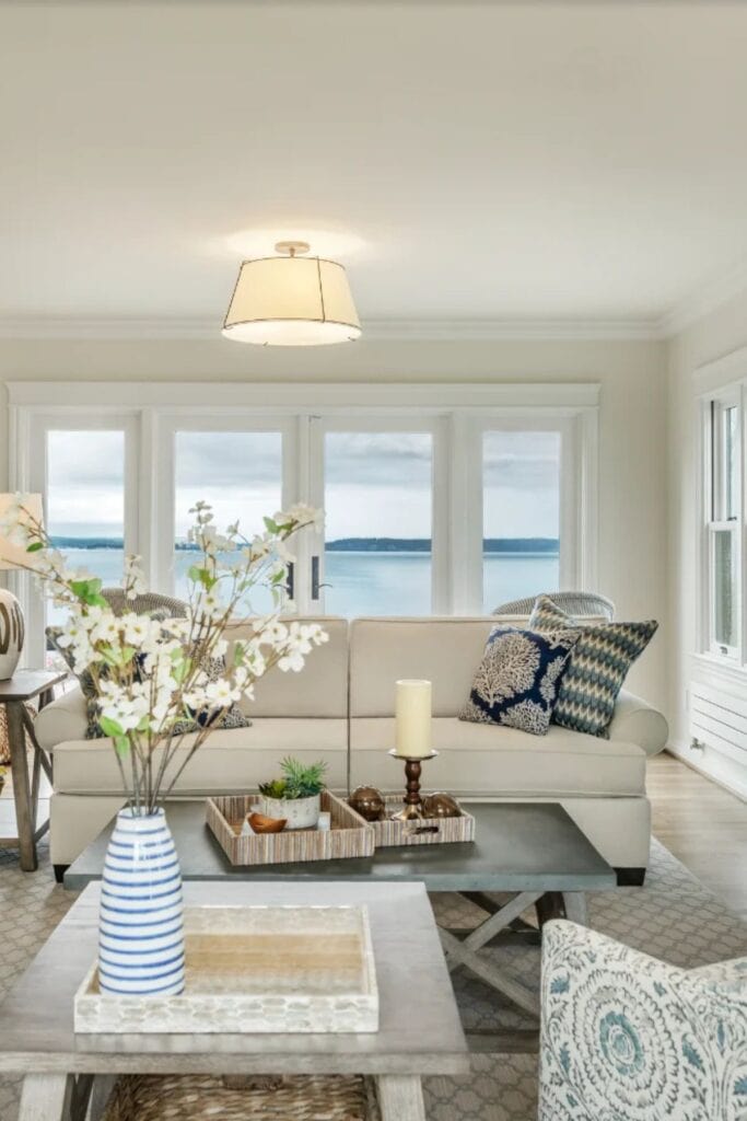 Sherwin Williams OYster White on the walls with a large set of windows in the back, a beige couch with blue and white throw pillows.