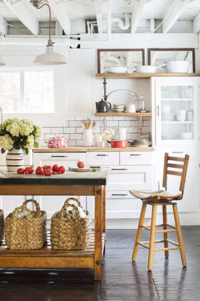 A white kitchen with a shelf extending above the cabinets that has mirrors and white cookware on it.
