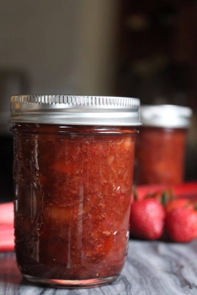 Strawberry rhubarb jam in mason jars with silver lids.