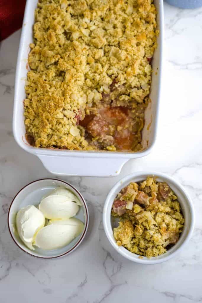 Strawberry rhubarb crumble in a white 13x9 dish on a marble surface.