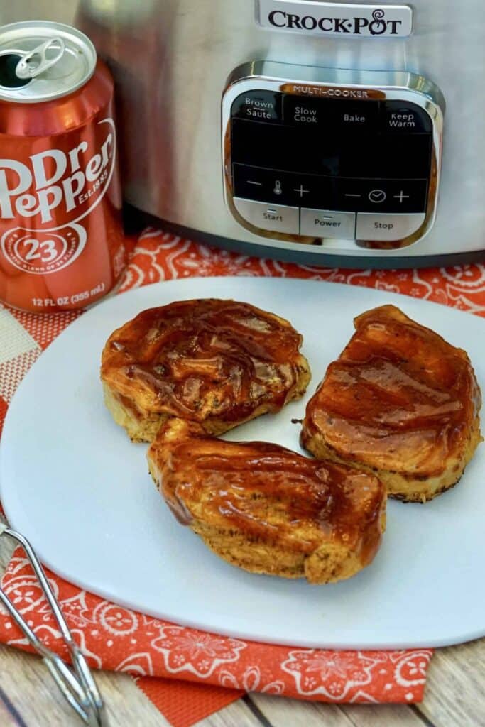 A crock pot with a dr. pepper can and a white plate with chicken