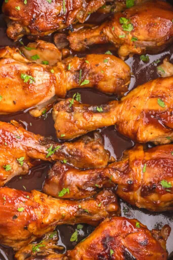 BBQ chicken legs in BBQ sauce with parsley sprinkled on top.