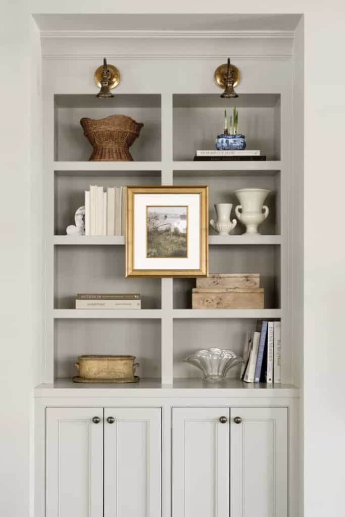 Built-ins holidng books and accessories with a framed lanscape photo hanging on the front of the built-ins.
