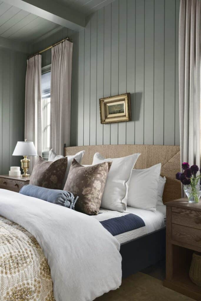 A bedroom with vertical shiplap, a woven headboard, lots of pillows and wood nightstands.